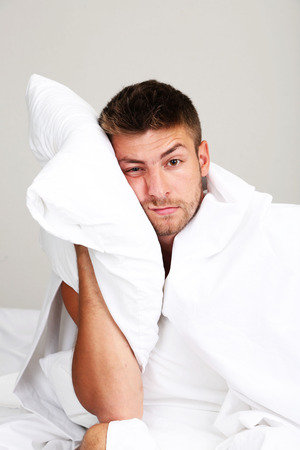 Handsome young man cant sleep in bedの写真素材
