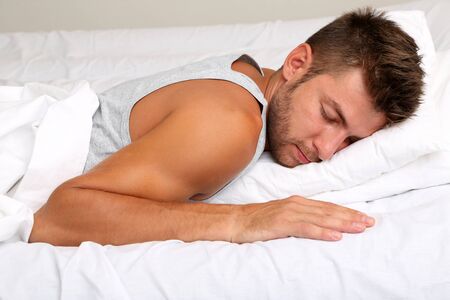 Handsome young man in bedの写真素材