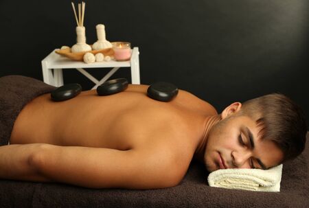 Young man relaxing with hot stones on back before massageの写真素材