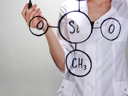 Chemist woman writing formulas on glass on grey backgroundの写真素材