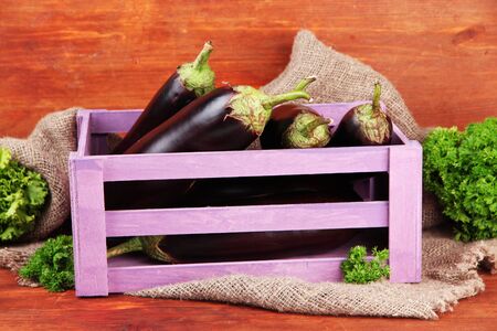 Fresh eggplants in wooden box on table on wooden backgroundの写真素材