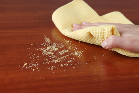 Hand wiping wooden surface with yellow rag