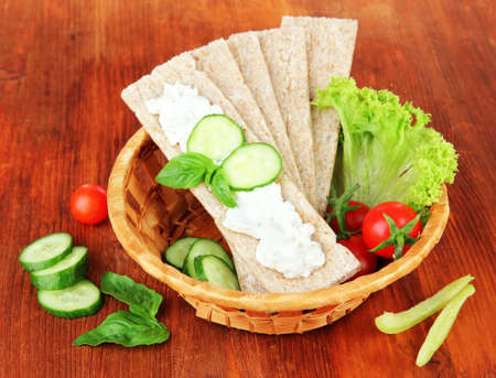Tasty crispbreads with vegetables on wooden backgroundの写真素材