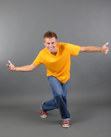 Handsome young man dancing on grey backgroundの写真素材