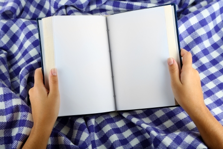 Book in hands on plaid backgroundの写真素材