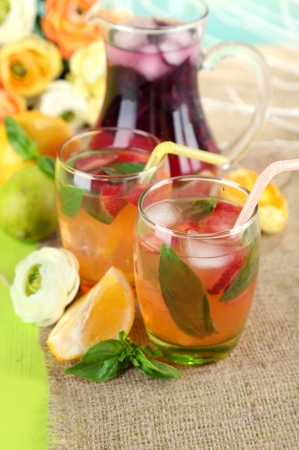 Red basil lemonade in jug and glass, on wooden table, on bright backgroundの写真素材