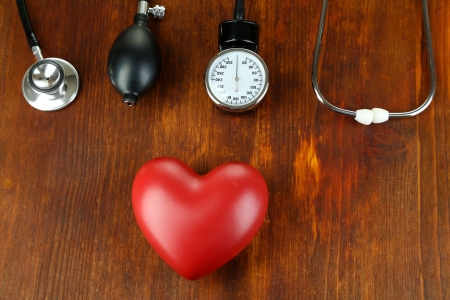 Tonometer, stethoscope and heart on wooden table close-upの写真素材