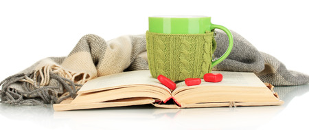 Cup with knitted thing on it and open book isolated on whiteの写真素材