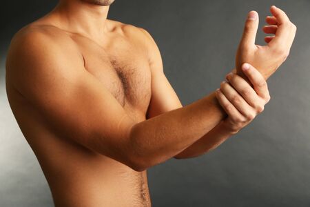 Young man with hand pain on grey backgroundの写真素材