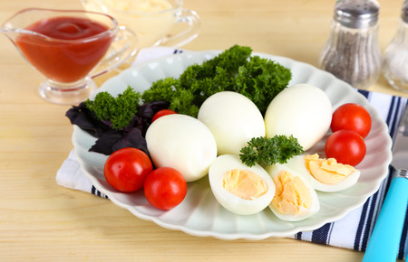 Boiled eggs on plate on napkin on wooden tableの写真素材