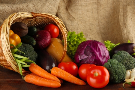 Different vegetables in basket on table on sackcloth backgroundの写真素材