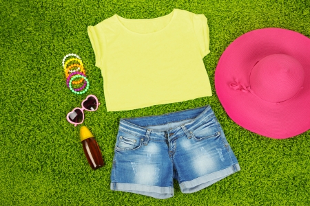 Top, shorts and beach items on bright green backgroundの写真素材