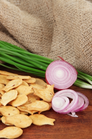 Delicious crackers with onions on wooden table on sackcloth backgroundの写真素材