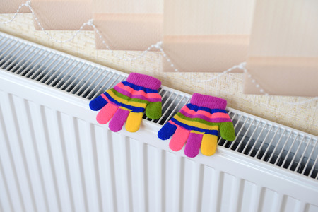 Knitted gloves drying on heating radiatorの写真素材