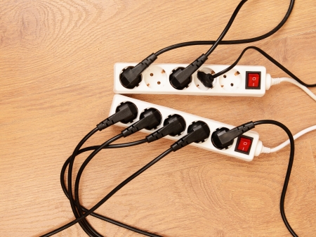 Overloaded power boards, on wooden floor background