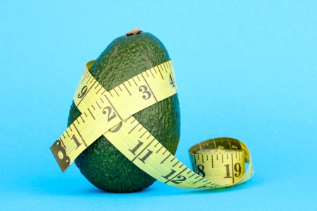 avocado with measuring tape on blue backgroundの写真素材