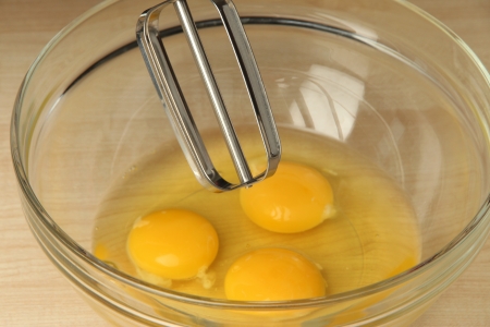 Cooking, whipping eggs with electric whisk in bowl, close upの写真素材