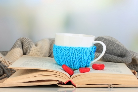 Cup with knitted thing on it and open book close upの写真素材