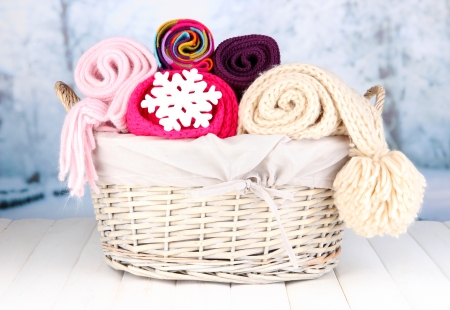 Warm knitted scarves in basket on winter backgroundの写真素材