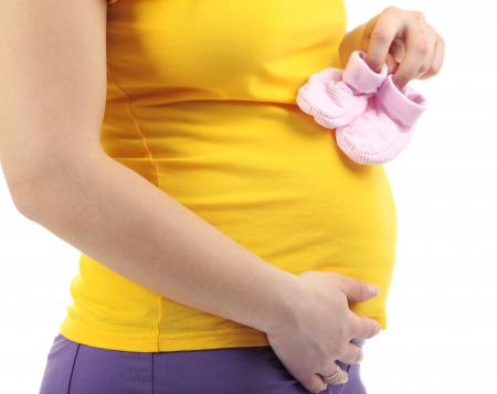 Pregnant woman holding pink baby shoes isolated on white