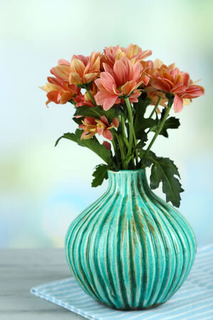 Beautiful flowers  in vase, on wooden table, on light backgroundの写真素材