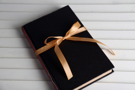 Book wrapped with color ribbon, on wooden backgroundの写真素材