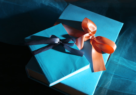 Books wrapped with color ribbon, on wooden table on dark backgroundの写真素材