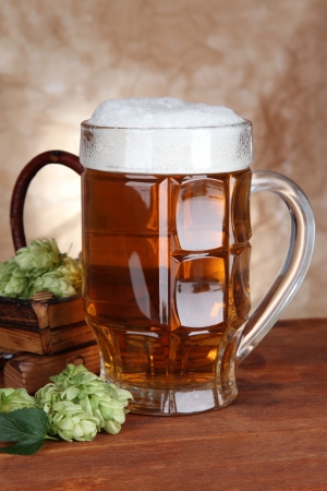 Glass of beer and hops, on wooden tableの写真素材