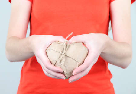 Woman hands holding a heart wrapped in brown kraft paper