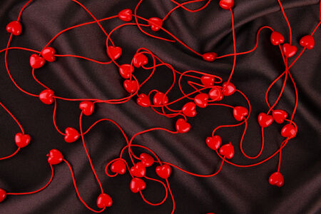 Heart-shaped beads on string on fabric background
