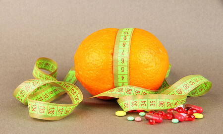 Orange with measuring tape and multicolor pills, on color backgroundの写真素材