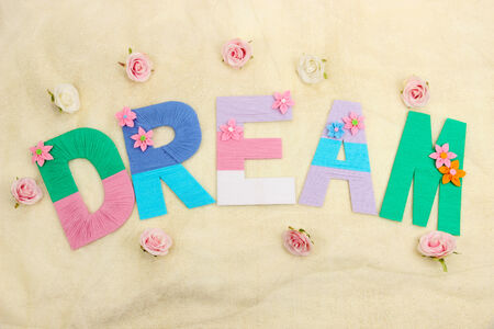 Word Dream created with brightly colored knitting yard on fabric background