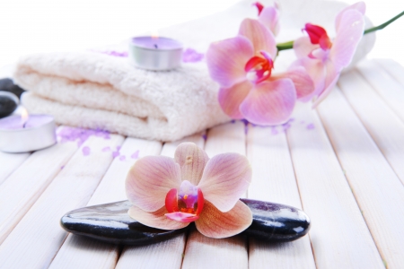 Still life with beautiful blooming orchid flower, towel and spa stones, on color wooden backgroundの写真素材