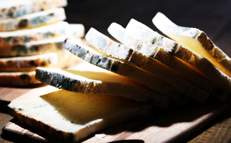 Mouldy bread on cutting board, on wooden background