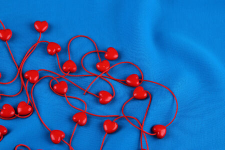 Heart-shaped beads on string on fabric backgroundの写真素材