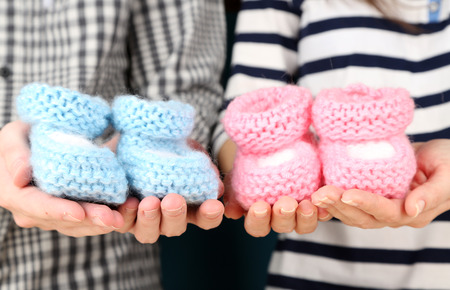 Hands with crocheted booties for baby, close-up