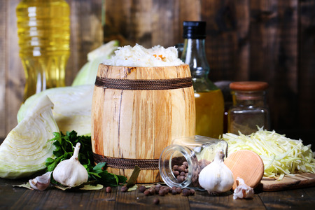 Composition with fresh and marinated cabbage (sauerkraut) in wooden barrel, on wooden table の写真素材