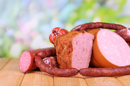 Lot of different sausages on wooden table on natural backgroundの写真素材