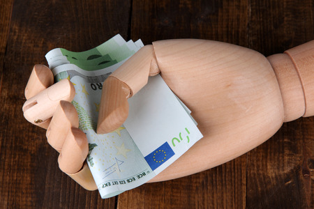 Money in wooden hand, on  color wooden table の写真素材