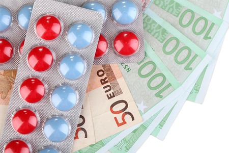 Prescription drugs on money background representing rising health care costs. Isolated on whiteの写真素材