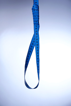 Tape measure noose on blue background - diet conceptの写真素材