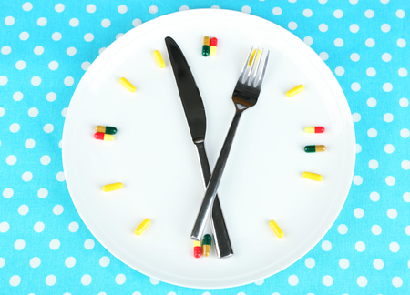 Medication schedule and meals. Conceptual photo. On color napkin backgroundの写真素材