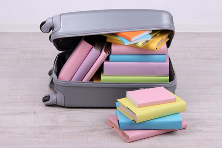 Books in suitcase on wall background