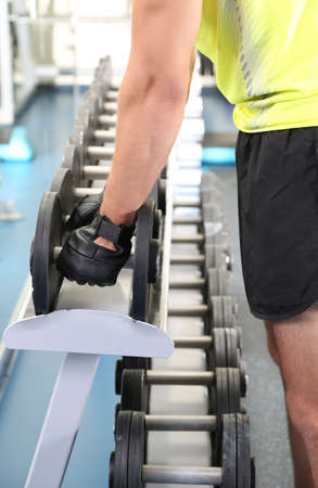 Guy with dumbbells on gym background close-up