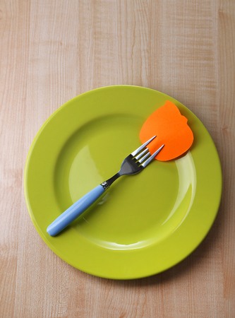 Empty note paper attached to fork, on plate, on color wooden background の写真素材