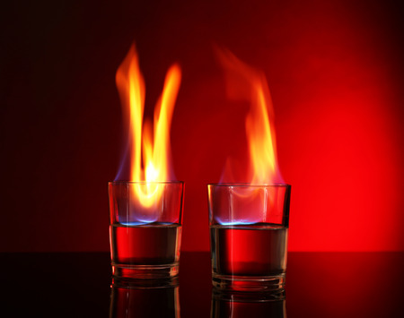 Glasses with burning alcohol on red backgroundの写真素材