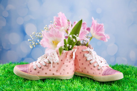 Beautiful gumshoes with flowers inside on green grass, on bright backgroundの写真素材