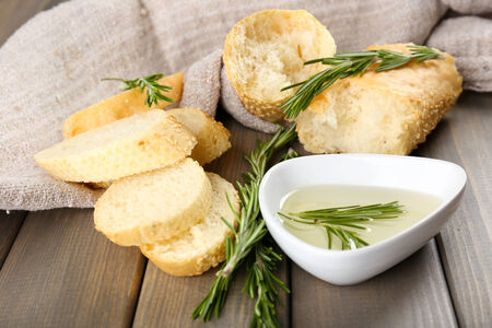 Fresh bread with olive oil and rosemary on wooden tableの写真素材