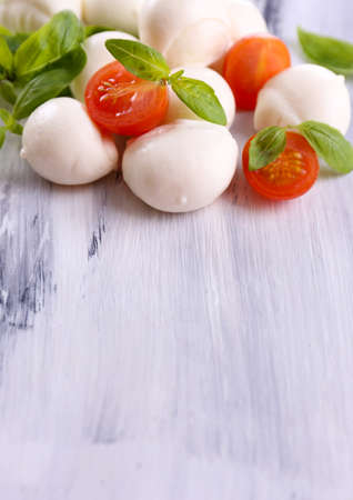 Tasty mozzarella cheese with basil and tomatoes, on wooden tableの写真素材