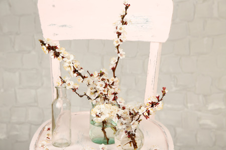 Beautiful apricot blossom in transparent jars on grey wall backgroundの写真素材